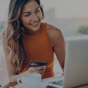 a woman holding a credit card typing on a laptop