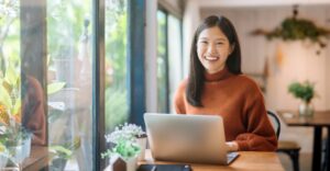 Woman smiling while using a laptop in a cafe