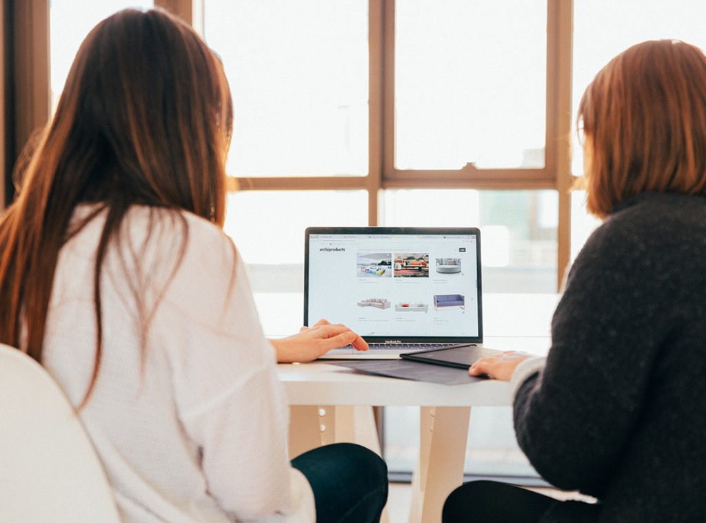 two women looking at a website on a laptop